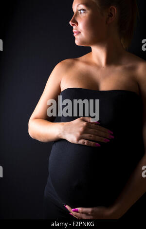 Belle femme enceinte se tenir avec les mains au ventre Banque D'Images