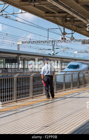 Un membre du personnel de la station qui veillaient sur une plate-forme tout en Shinkansen, le train passe un Banque D'Images