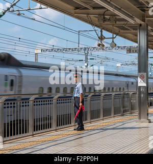 Un membre du personnel de la station qui veillaient sur une plate-forme tout en Shinkansen, le train passe un Banque D'Images