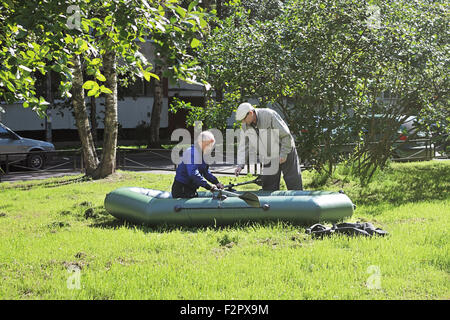 Deux hommes sont formés pour gérer un bateau en caoutchouc sur l'herbe près de chez eux Banque D'Images