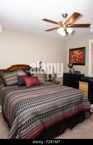 Vue de la chambre d'une maison, y compris un lit et une commode, d'un ventilateur de plafond. Banque D'Images