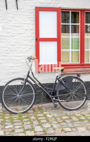 Un vélo stationné à une fenêtre sur rue de Bruges en Belgique Banque D'Images