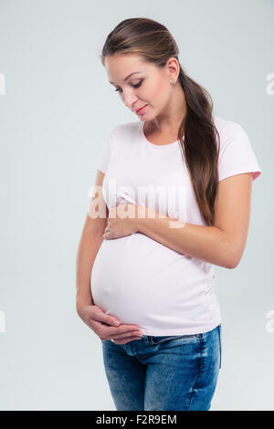Portrait d'une femme enceinte en caressant son ventre isolé sur fond blanc Banque D'Images