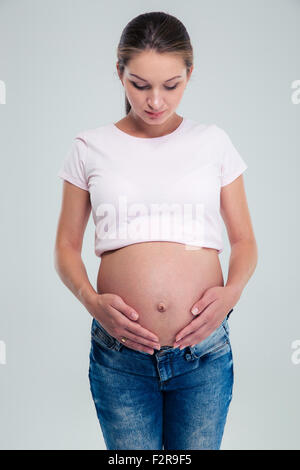 Portrait d'une femme enceinte debout sur fond gris Banque D'Images