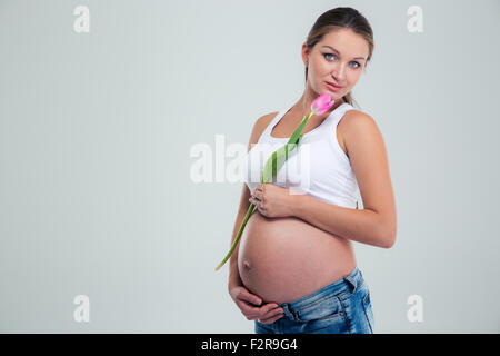 Portrait of a beautiful pregnant woman standing with flower isolated on a white background Banque D'Images