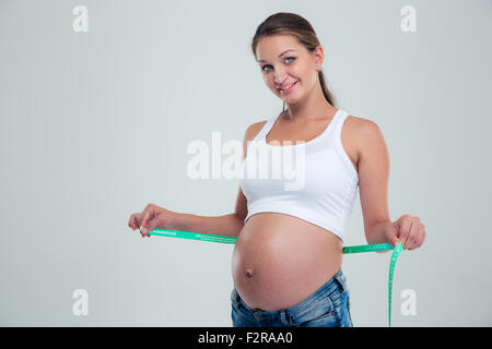 Portrait of a happy pregnant woman avec ruban de mesure isolé sur fond blanc Banque D'Images