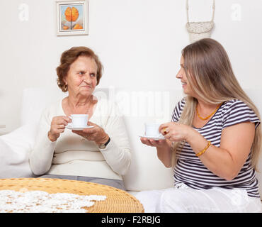 Soignant ayant une tasse de thé avec une vieille femme à la retraite Banque D'Images