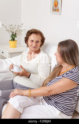 Soignant ayant une tasse de thé avec une vieille femme à la retraite Banque D'Images