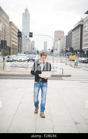 Young handsome young businessman walking contemporain sur la rue à l'aide d'un ordinateur portable à l'écran vers le bas - la technologie, réseau, entreprise, finance concepts Banque D'Images