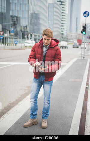 Young handsome young businessman walking contemporain à travers la ville à l'aide d'une tablette à l'écran - la technologie, réseau, entreprise, finance concepts Banque D'Images