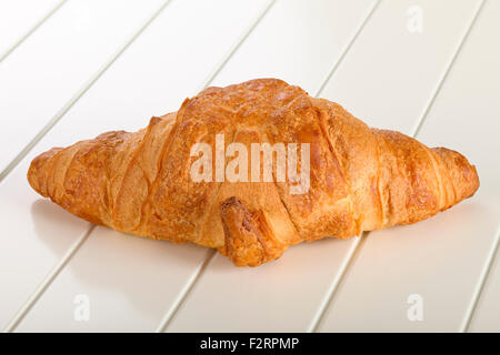 Croissant sucré avec du chocolat sur fond de bois blanc. Banque D'Images