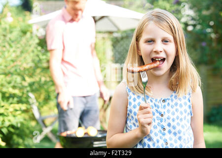 Girl Eating Sausage au barbecue familial Banque D'Images