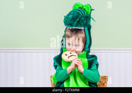 Adorable petit garçon dans un costume de crocodile mange un cookie d'Halloween Banque D'Images