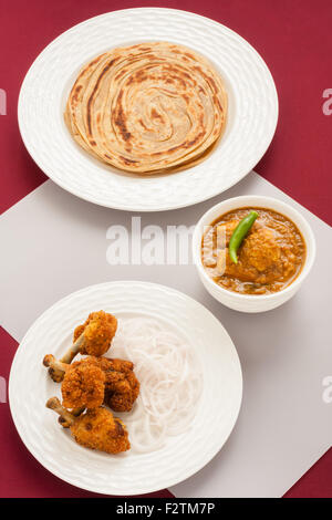 Vue aérienne de sucettes de poulet frit servi avec poulet au curry indien et le blé (pain indien parotta) comme un repas. Banque D'Images