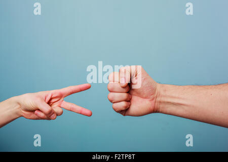 Jeune homme et femme jouent à pierre papier ciseaux Banque D'Images