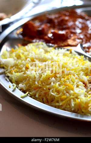 Gros plan de riz safrané et poulet au beurre dans un bac Banque D'Images