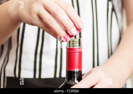 La main de femme se dévisse le bouchon à vis de bouteilles de vin rouge Banque D'Images