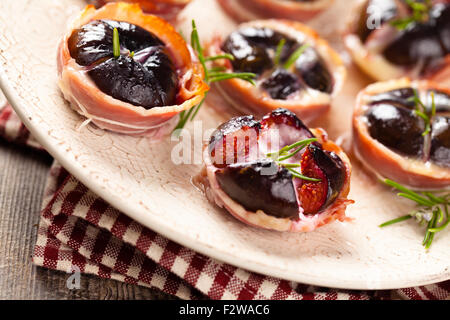 Figues au four avec du fromage et du romarin, enrobé de bacon. Banque D'Images
