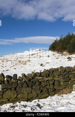 La colline couverte de neige au-delà d'un mur en pierre sèche près du réservoir d'Dovestone, Bellevue. Réservoir d'Dovestone se trouve entre Oldham et jours fériés Banque D'Images