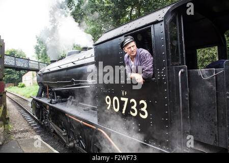 Le pilote du moteur de locomotive à vapeur, ingénieur conducteur de train dans la cabine d'austérité 90733 RM 2-8-0 à une station Banque D'Images