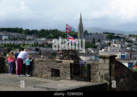 Les touristes en regardant les murs de Derry jeunes nationalistes debout sur un grand feu fait à partir de palettes en bois, dans le Bogside, Londres Banque D'Images