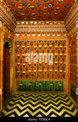 L'orange vif des murs intérieurs ornés de fleurs peintes avec des motifs de tessellation au City Palace, Udaipur, Rajasthan, Inde Banque D'Images
