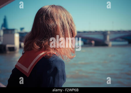 Une jeune femme en costume de marin est reposant sur un bateau sur la Tamise à Londres, Angleterre Banque D'Images