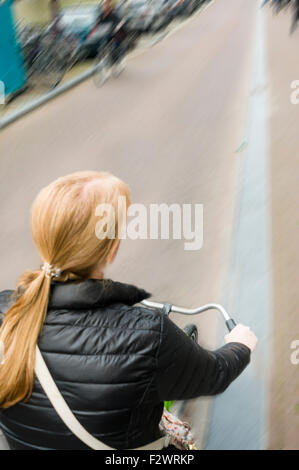 Une femme monte un vélo le long d'une rue à Amsterdam avec le motion blur Banque D'Images