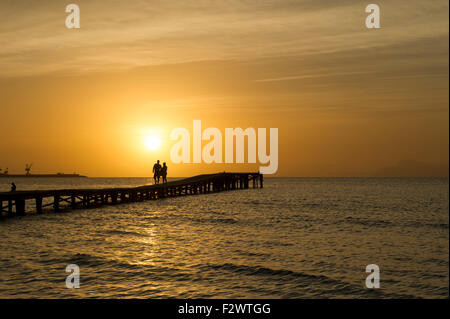 Couple en train de marcher sur la jetée en bois au lever du soleil. Port d'Alcuida, Mallorca, Espagne Banque D'Images