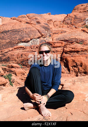 Femme se détend sur falaise au Red Rock Canyon National Conservation Area, à environ 20 minutes de Las Vegas ; elle pratique le highlining Banque D'Images