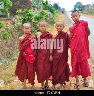 Quatre jeunes moines bouddhistes Theravada portant leurs robes au bord de la route au Myanmar (Birmanie, Birmanie, Asie) Banque D'Images