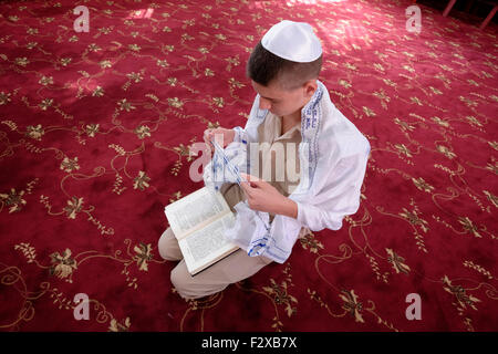 Les jeunes Juifs Karaïtes en uniforme s'inclinant sur les genoux pendant la prière dans une synagogue karaïte dans la ville de Ramle ou Ramleh Israël. Les Juifs Karaïtes qui refuse l'ajout ultérieur de la Bible juive comme la loi orale rabbinique se prosterner comme les musulmans quand ils prient Banque D'Images