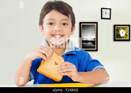 1 Indian kid boy eating Bread matin Petit déjeuner Banque D'Images