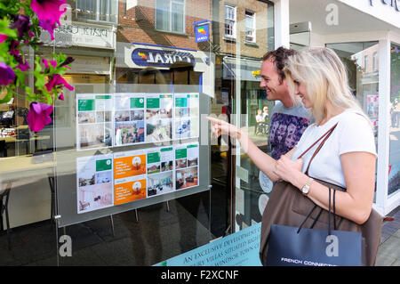 Jeune couple à la recherche de l'agent immobilier à fenêtre, Peascod Street, Windsor, Berkshire, Angleterre, Royaume-Uni Banque D'Images