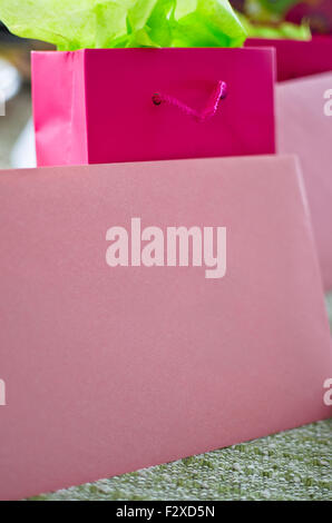 L'enveloppe rose et blanc avec le joli sac cadeau papier de soie vert vif. Banque D'Images