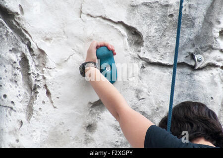 Young teen girl grimpe un mur d'escalade artificiel autorisation Modèle disponible Banque D'Images
