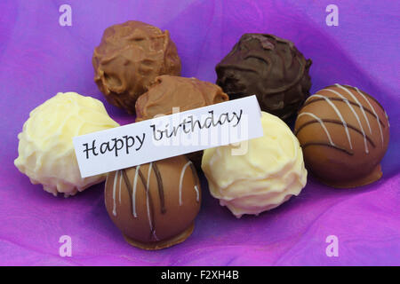 Joyeux anniversaire carte avec chocolats assortis sur fond violet Banque D'Images