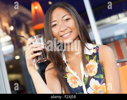 Close up portrait of a beautiful Asian girl de boire un soda assis sur la terrasse Banque D'Images