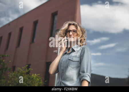 Les jeunes, confiant, femme d'affaires en hâte. Parler sur smartphone en marchant dans la rue. Portrait of businesswoman en ru Banque D'Images