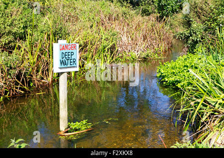 Danger - signe d'eau profonde dans la rivière Glaven à Glandford, Norfolk, Angleterre, Royaume-Uni. Banque D'Images