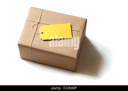 Paquet cadeau enveloppé dans du papier recyclé marron avec étiquette jaune blanc isolated on white Banque D'Images