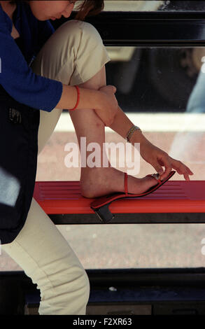 Femme repose à l'arrêt de bus avec des pieds endoloris pour ajuster ses chaussures sortir shopping (crédit de droit©Jack Ludlam) Banque D'Images