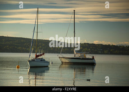 Deux yachts au mouillage dans le lac calme, paisible avec des collines derrière au lever du soleil. Banque D'Images