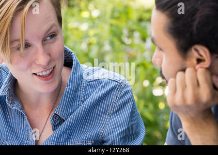 Portrait d'un jeune homme et une femme assis côte à côte, sourire et parler. Banque D'Images