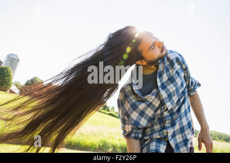 Un jeune homme laisser tomber ses très longs cheveux noirs et de secouer la tête de ventilateur il à l'air frais. Banque D'Images
