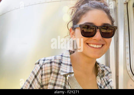 Une jeune femme portant des lunettes de soleil par une remorque de couleur argent. Banque D'Images