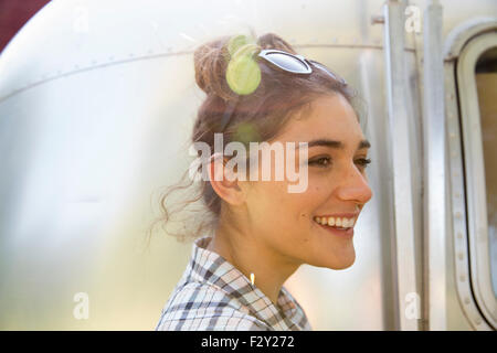 Une jeune femme portant des lunettes de soleil par une remorque de couleur argent. Banque D'Images