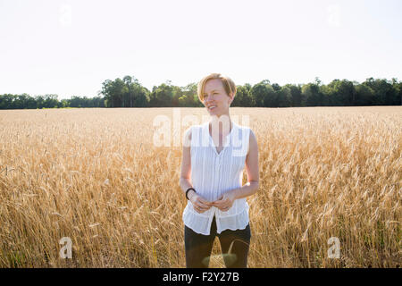 Demi-longueur portrait d'une jeune femme debout dans un champ de maïs. Banque D'Images