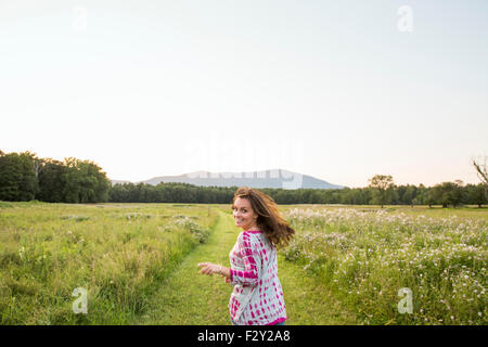 Femme en marche le long d'un chemin dans un pré, à à l'épaule. Banque D'Images