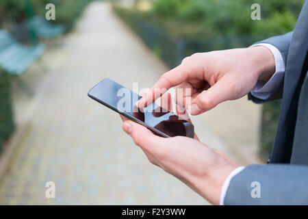 L'homme à l'aide d'un téléphone cellulaire au parc. close-up hands Banque D'Images